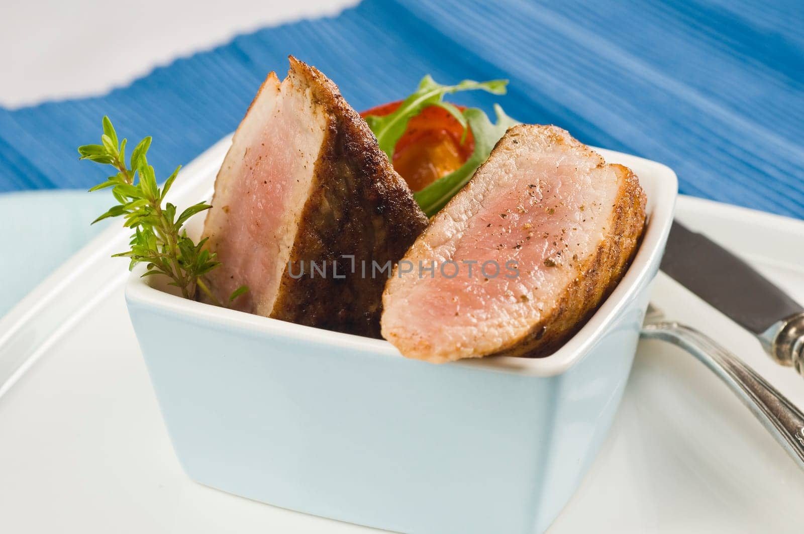 Pork tenderloin,fried in light blue bowl with herbs
