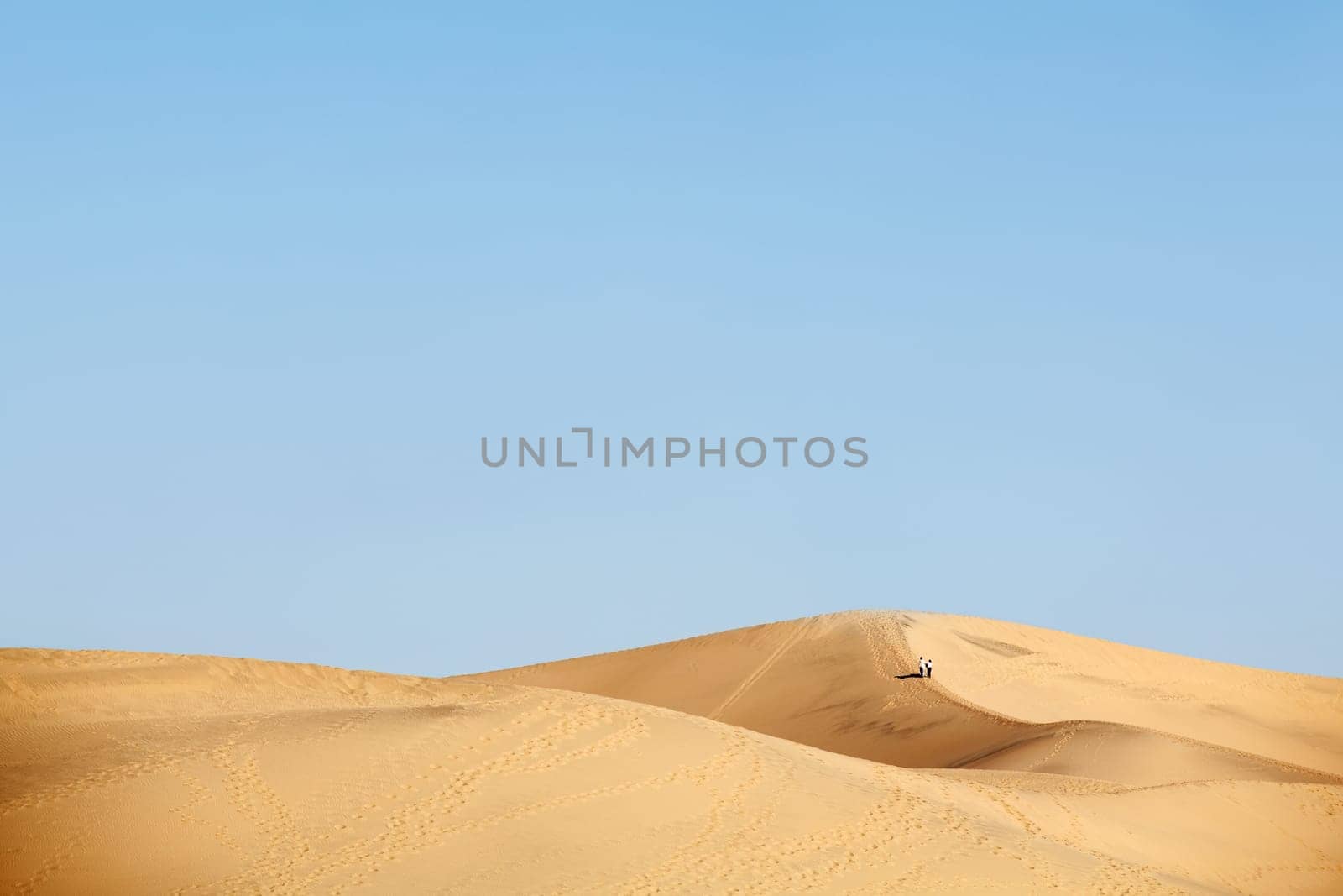 two people walking in desert dunes