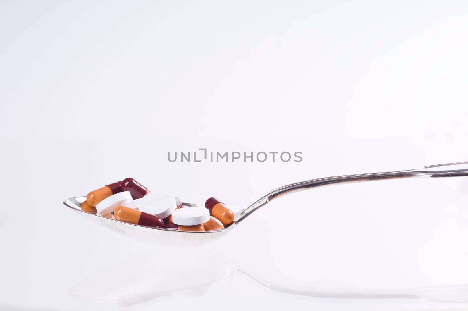 Various tablets in spoon on white background