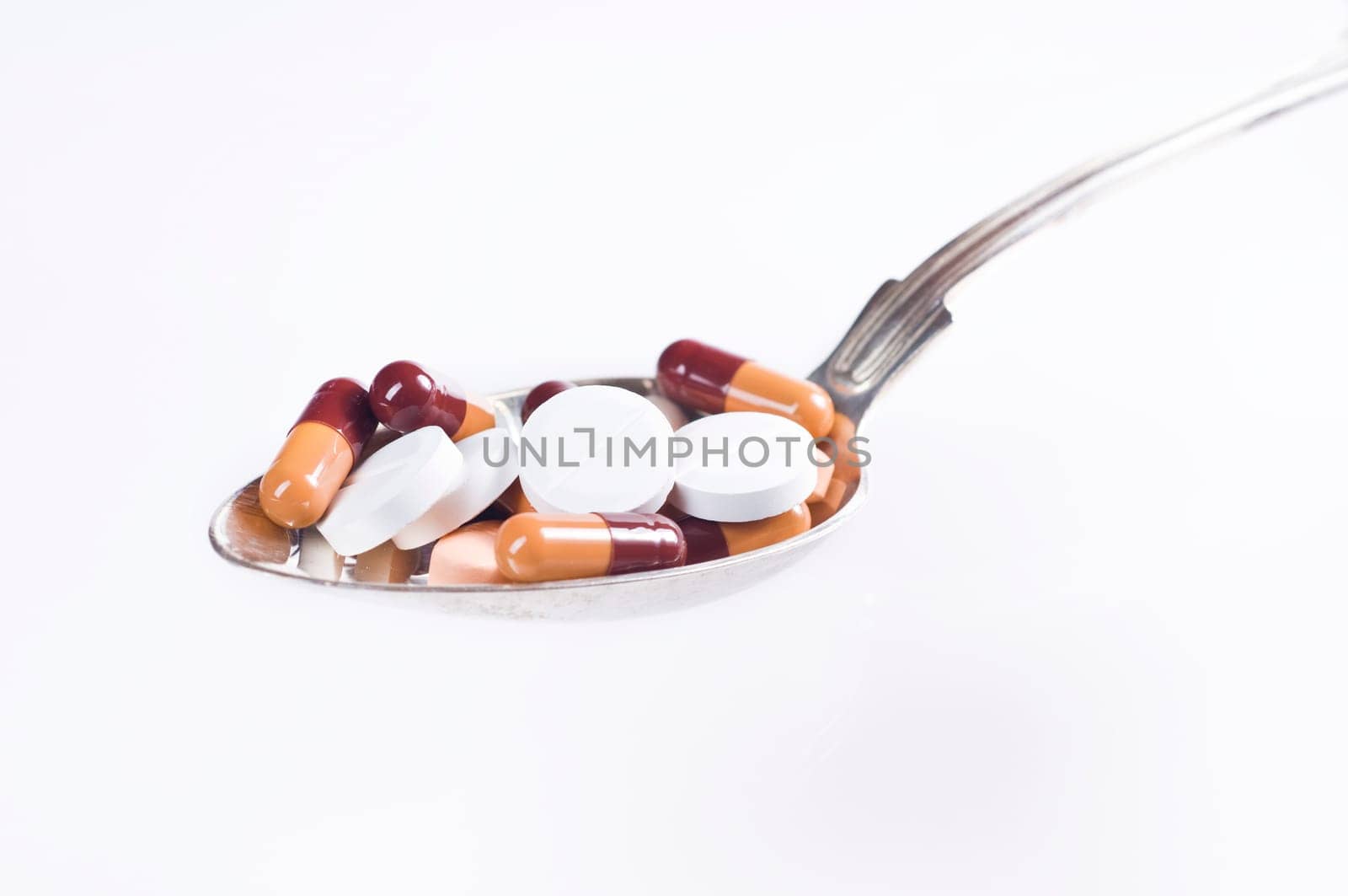 Various tablets in spoon on white background