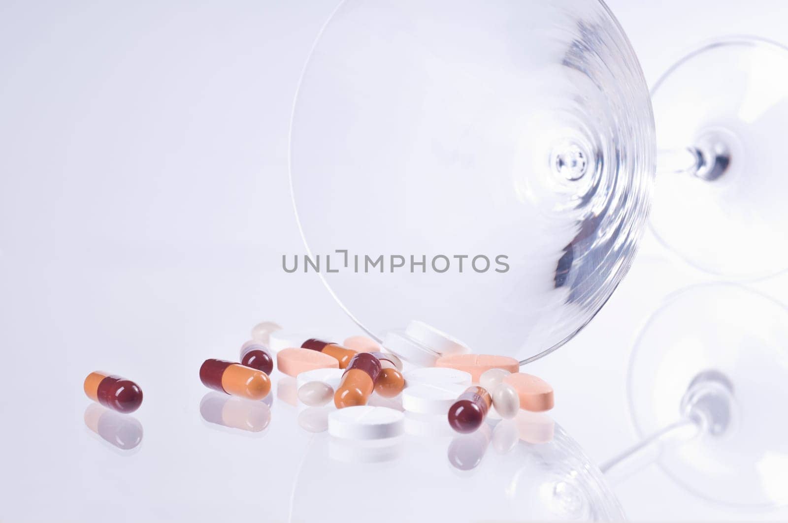 Various tablets in cocktail glass on white background
