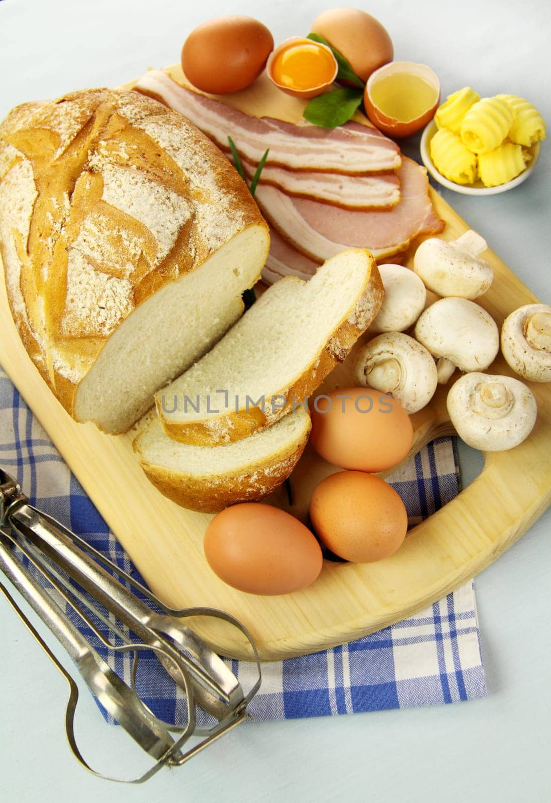 Bread, bacon, eggs and mushrooms ready to be cooked for breakfast.