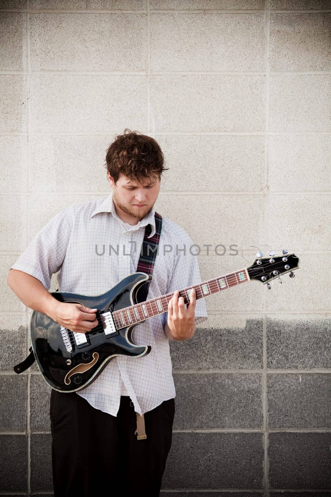 man playing guitar against wall