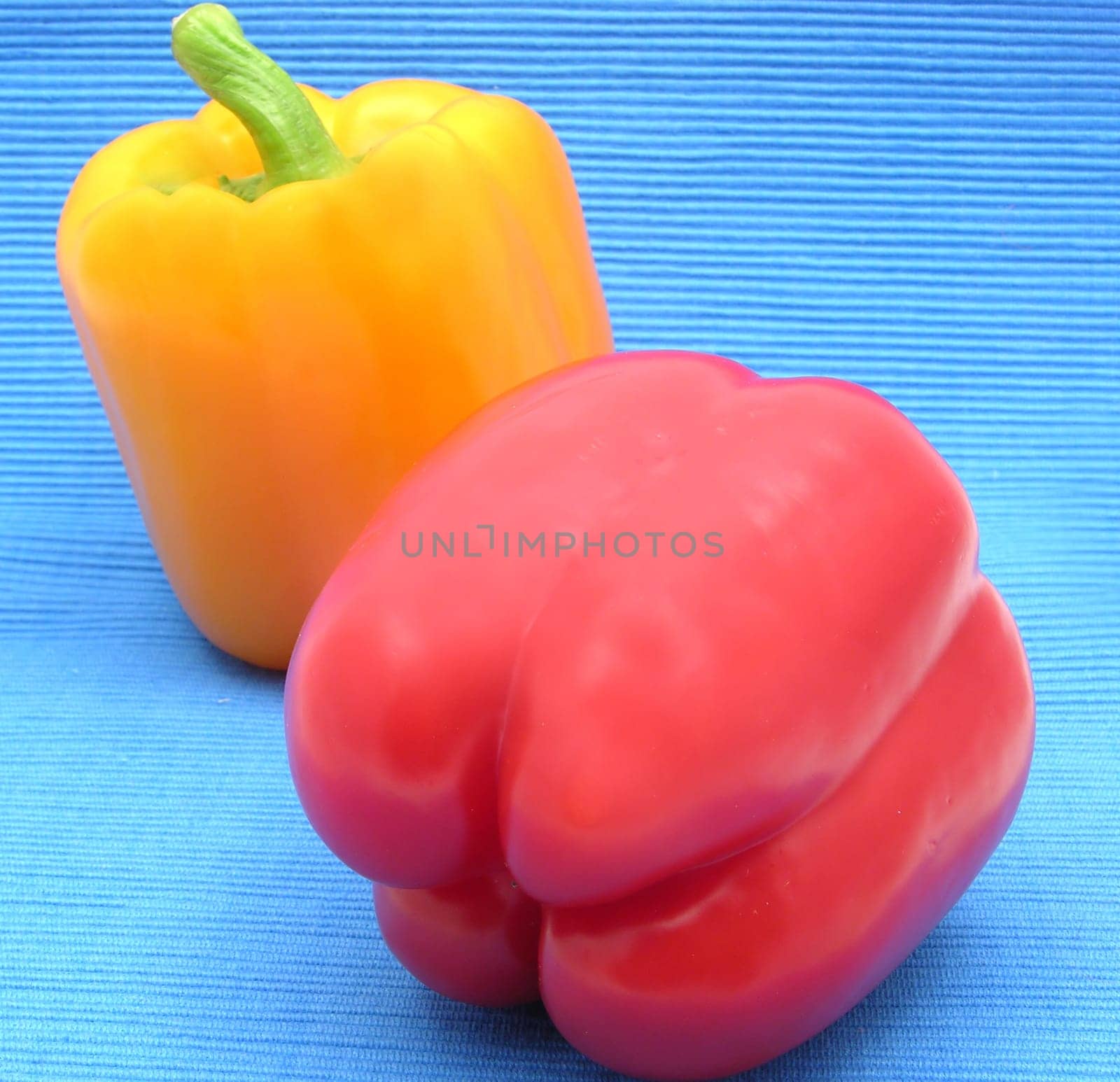 Red and yellow bell pepper against blue background