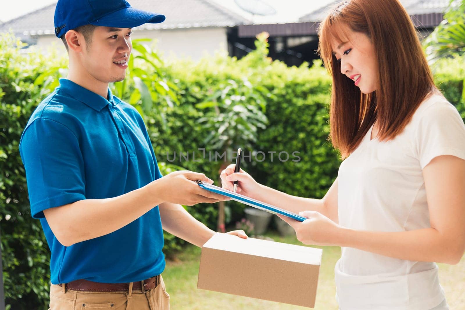 woman signing delivery in clipboard get her package from service courier man by Sorapop