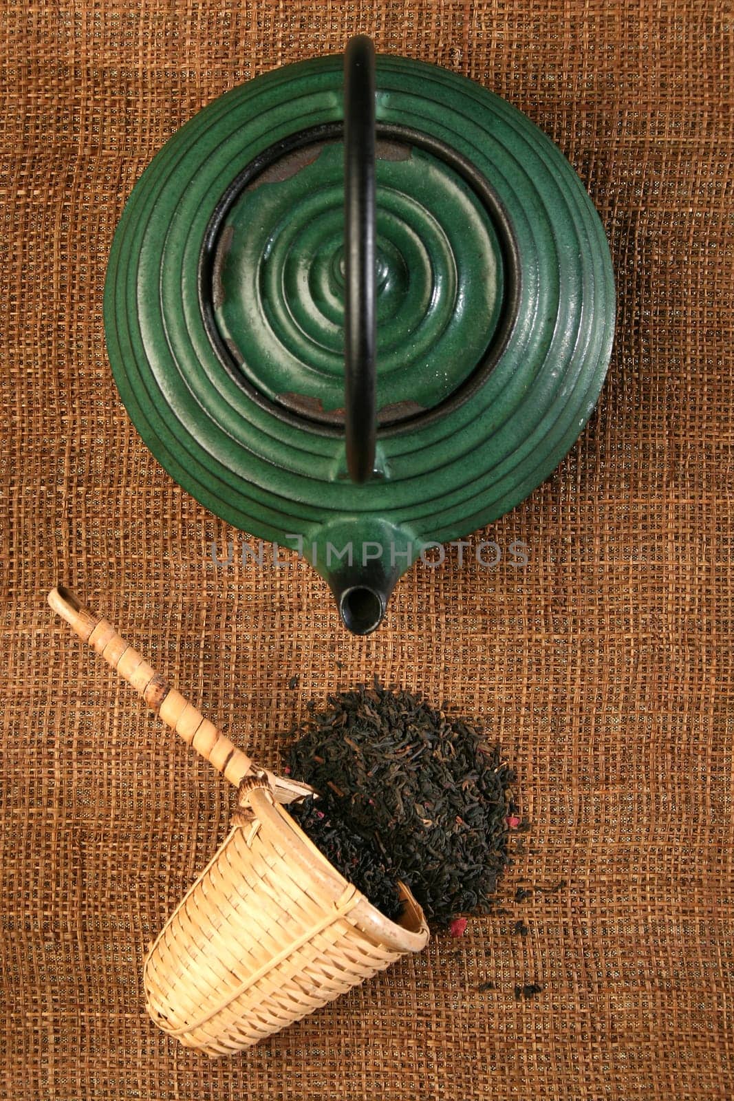 Chinese teapot and a wicker scoop with herb tea leaves