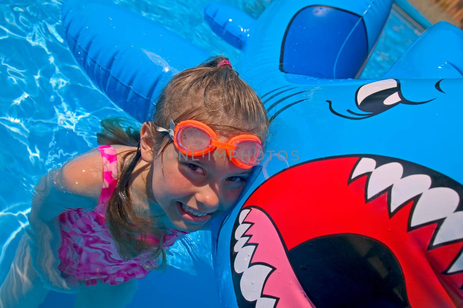 Girl playing in swimming pool with inflatable shark