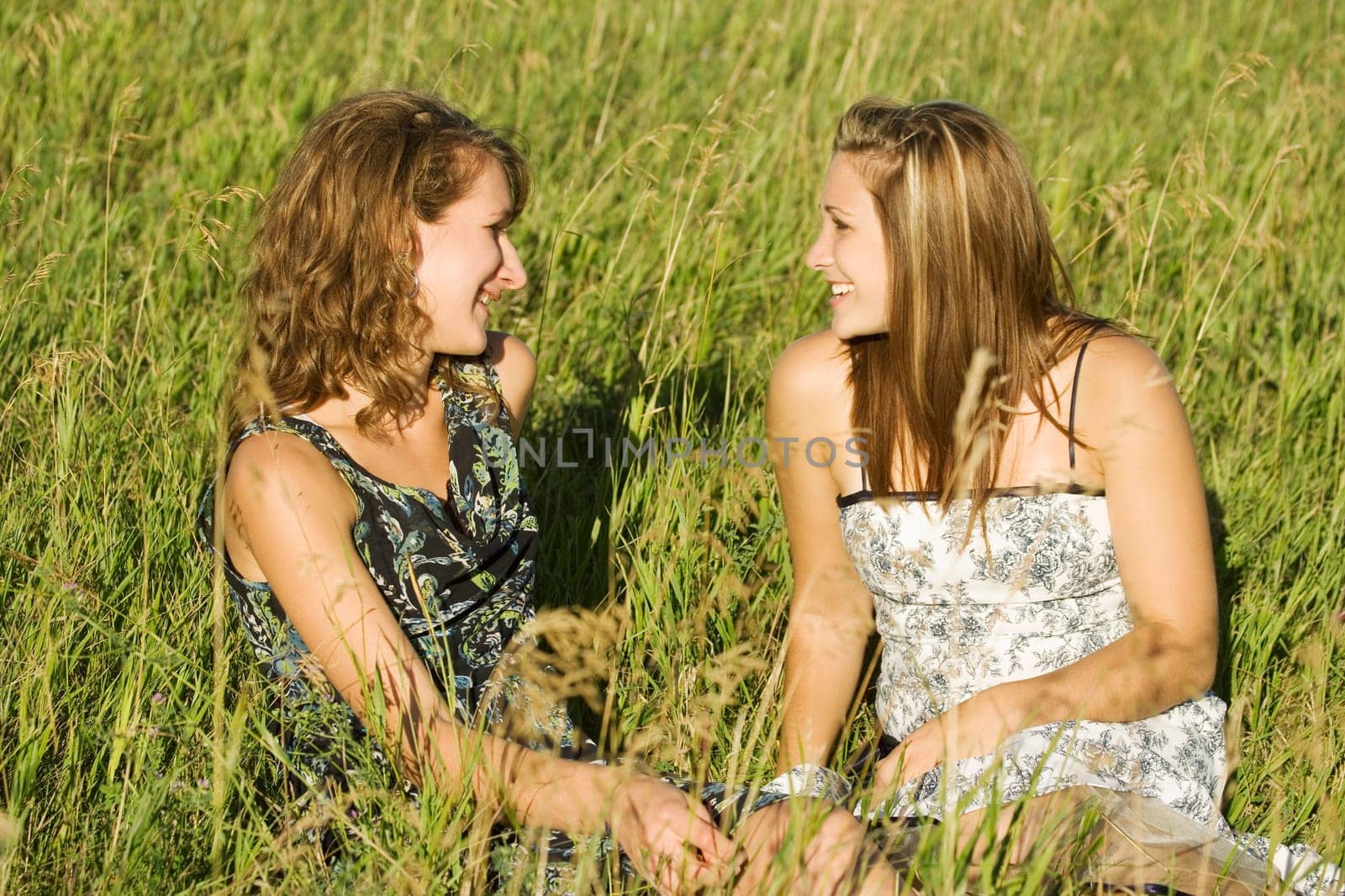 Two women sitting in field talking