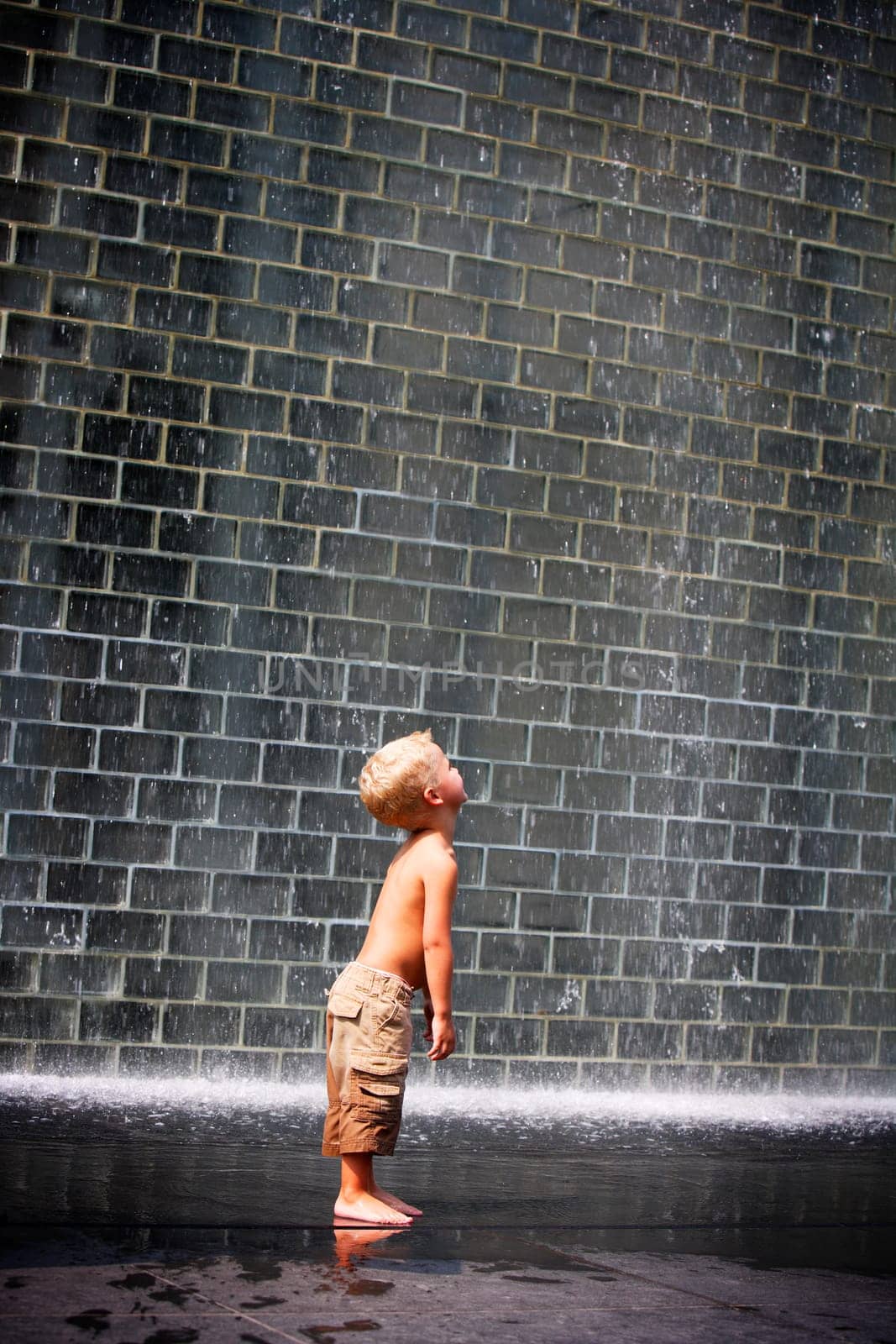 A boy standing beside a wall fountain, Chicago, Illinois, USA