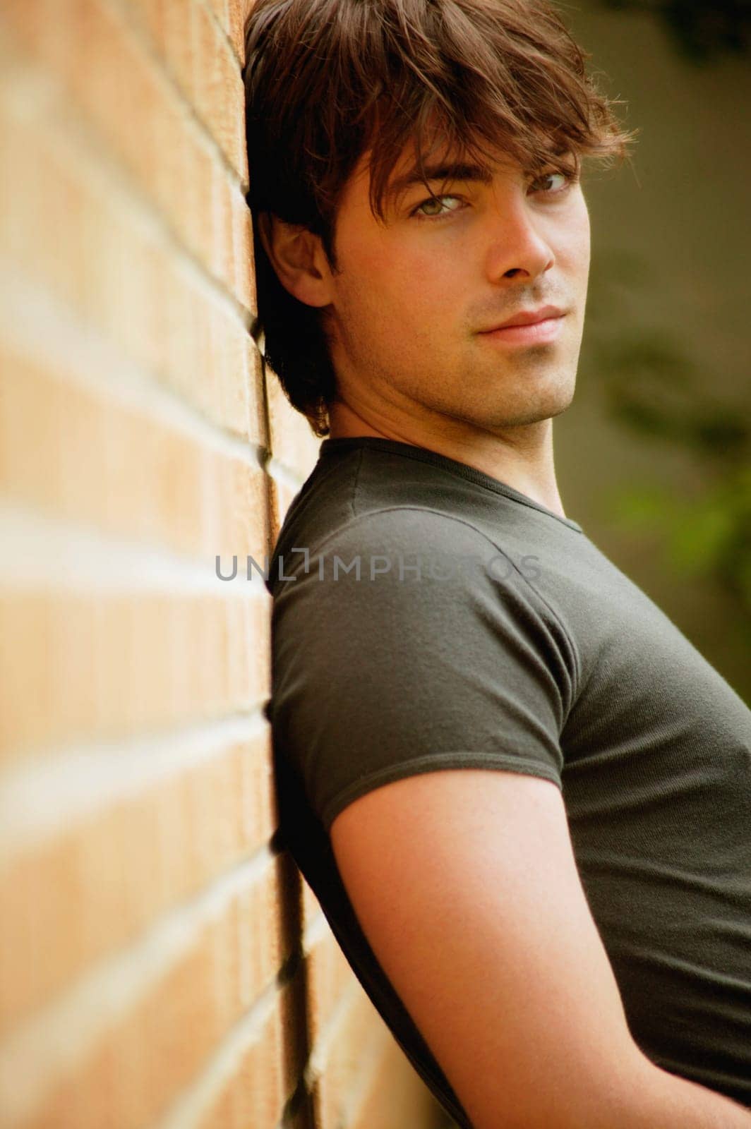 Man leans against brick wall