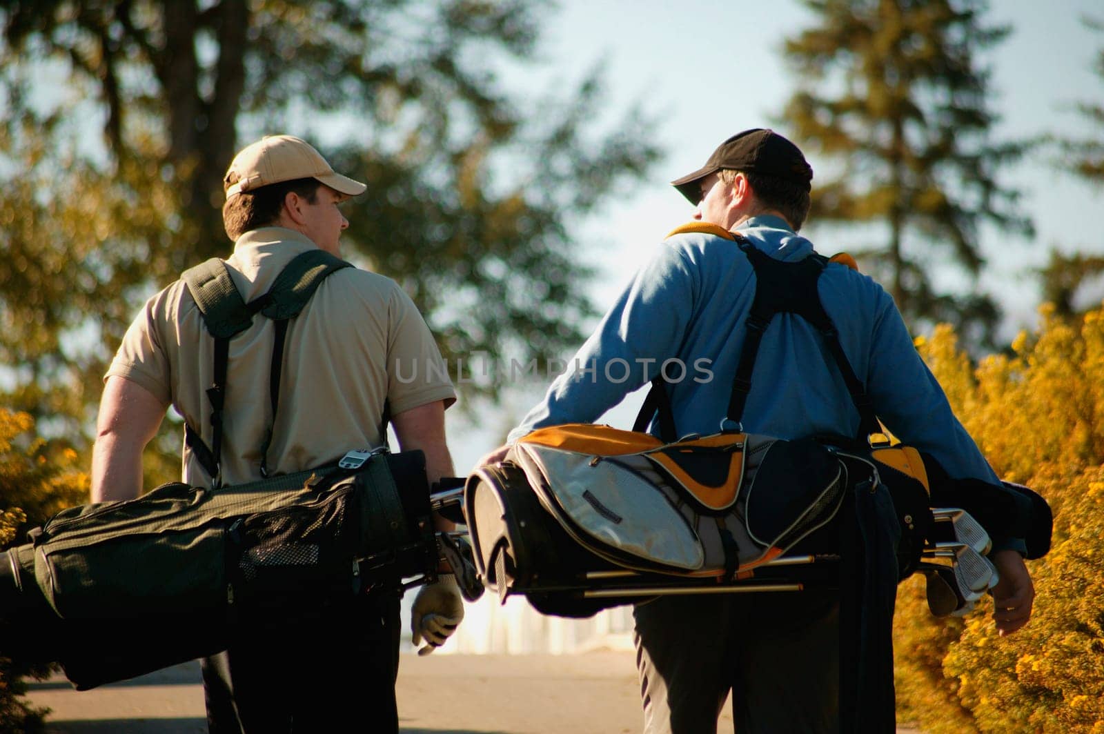 Two men carry golf bags