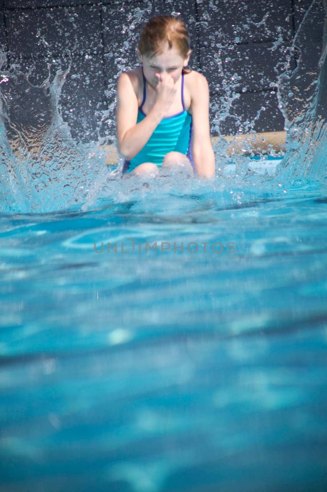 Girl splashes in swimming pool