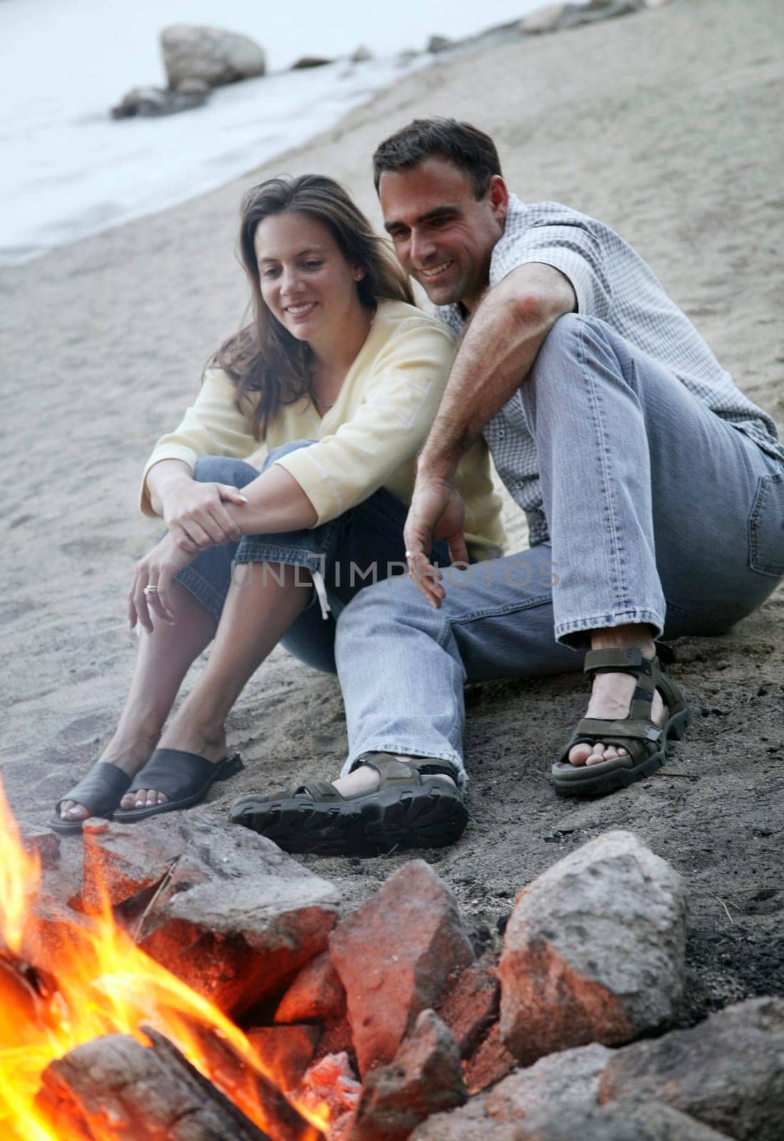 Couple keep warm by campfire