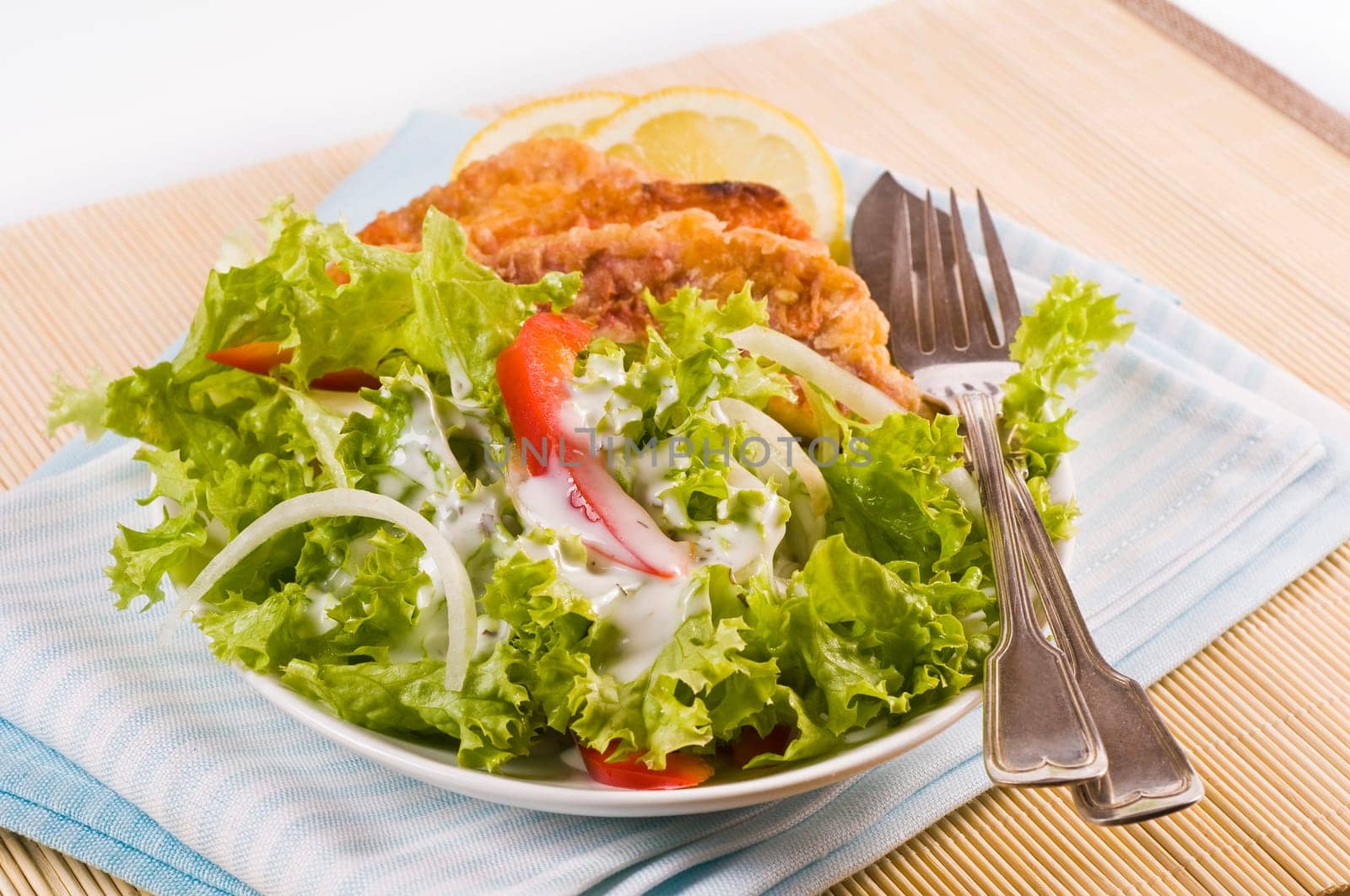 Lettuce with fried mullet fillet served in a white salad bowl