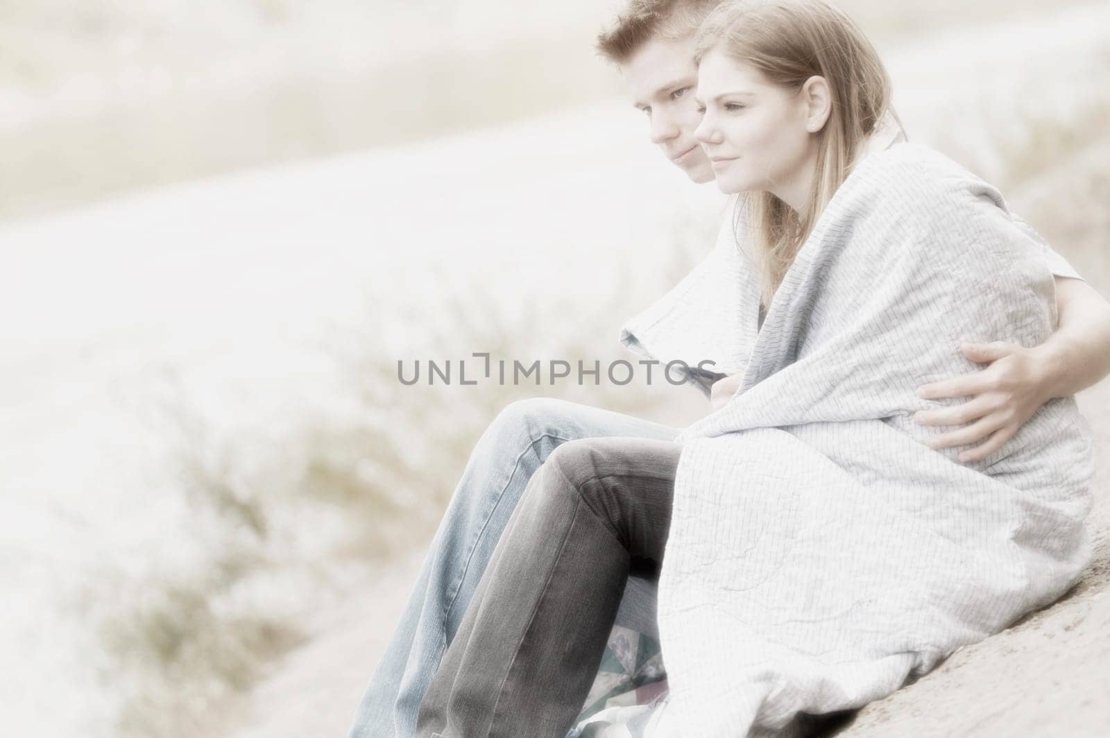 Couple sitting on beach with blanket