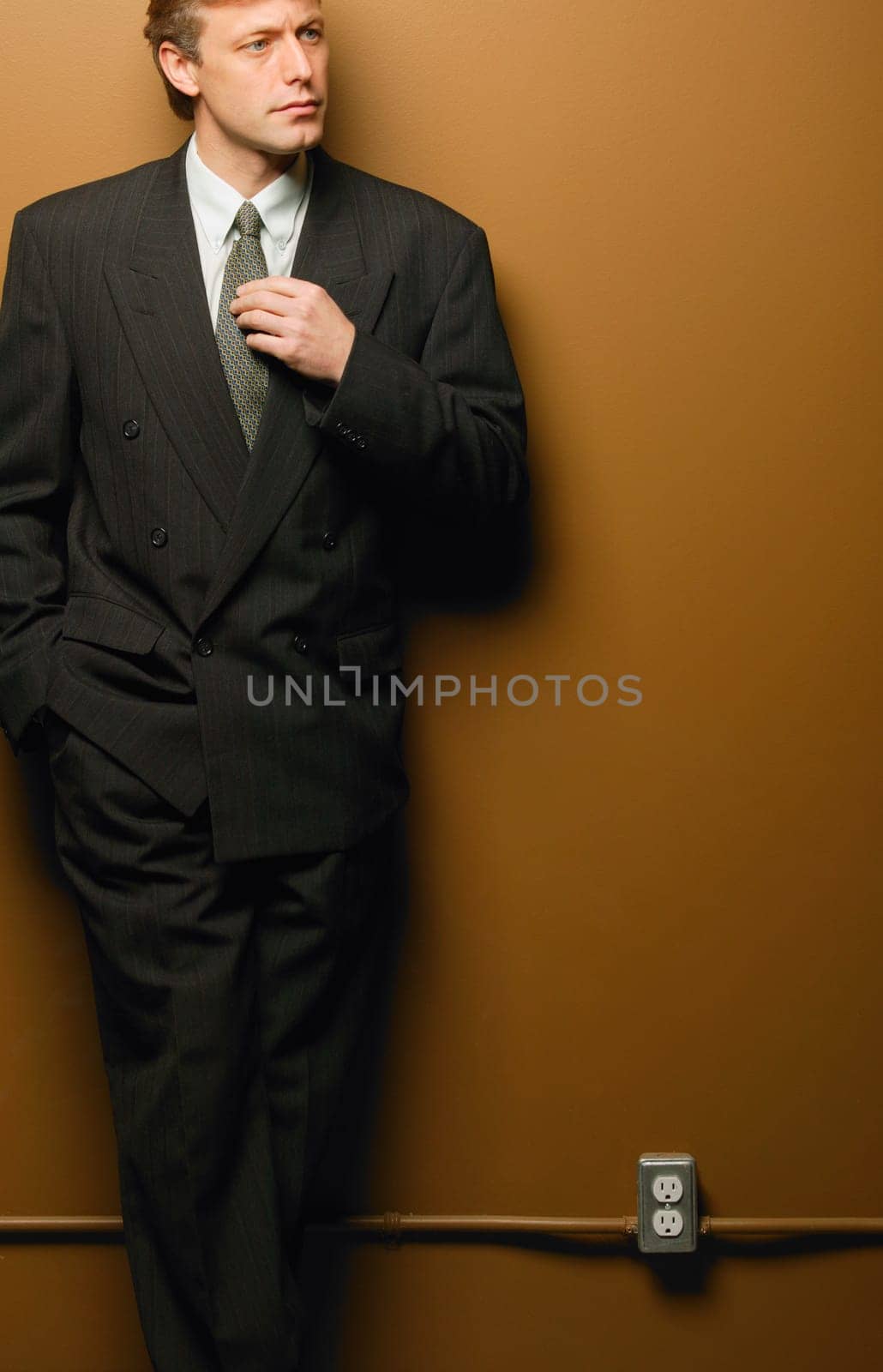 Businessman leaning on interior wall
