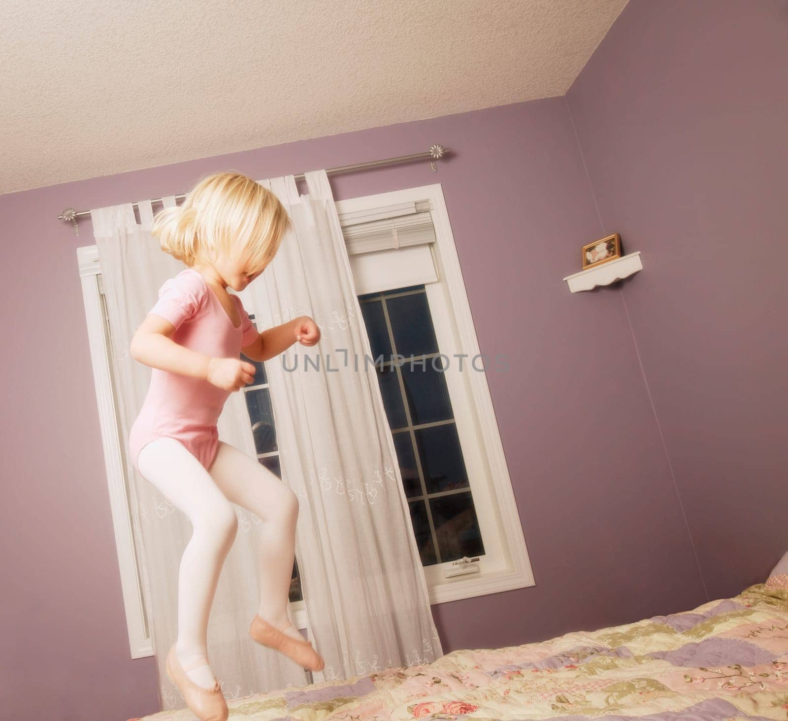 Young girl jumping on bed