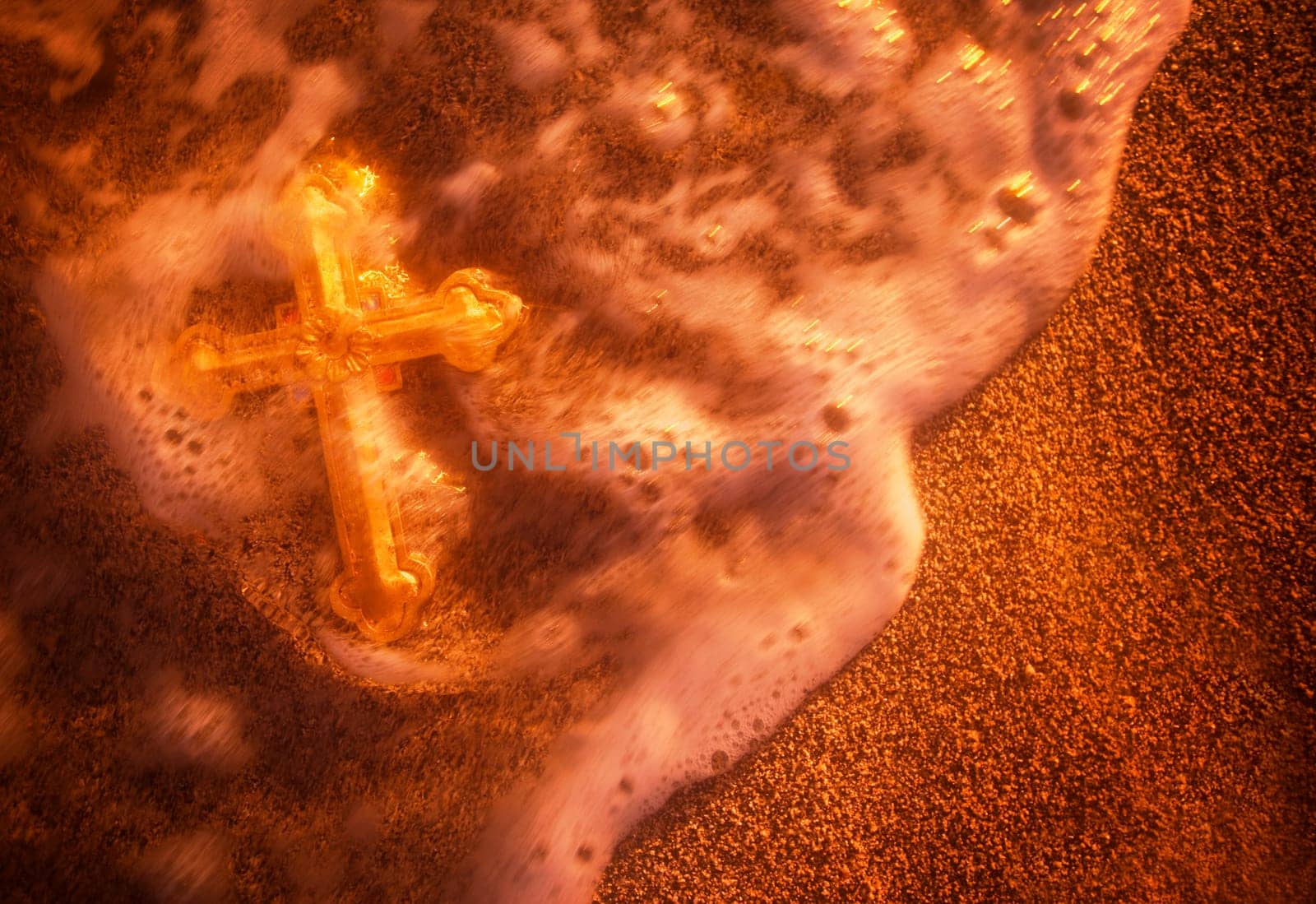 Cross being washed over by wave on sandy beach