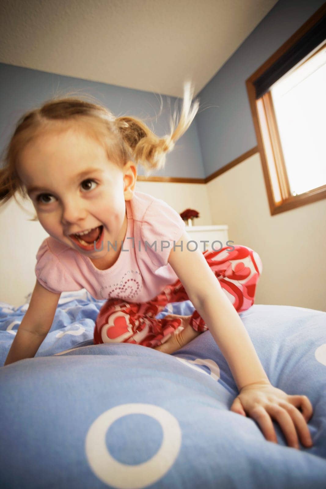 Young girl bouncing on bed