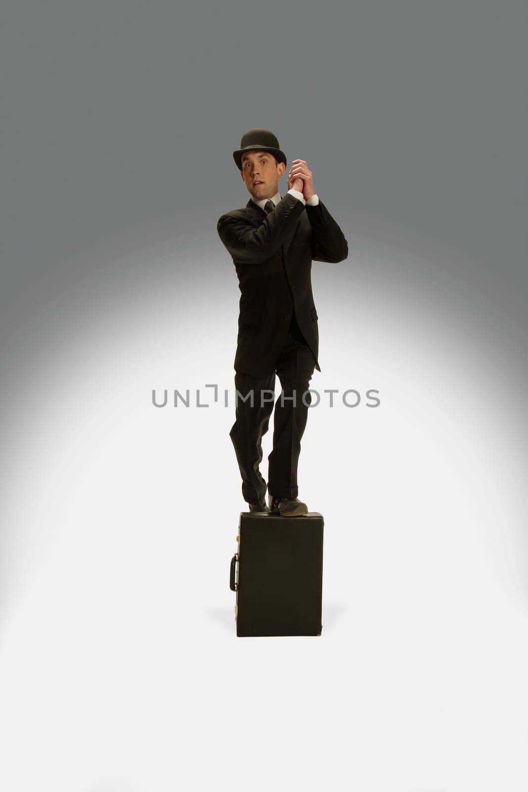 A winning businessman stands on his briefcase
