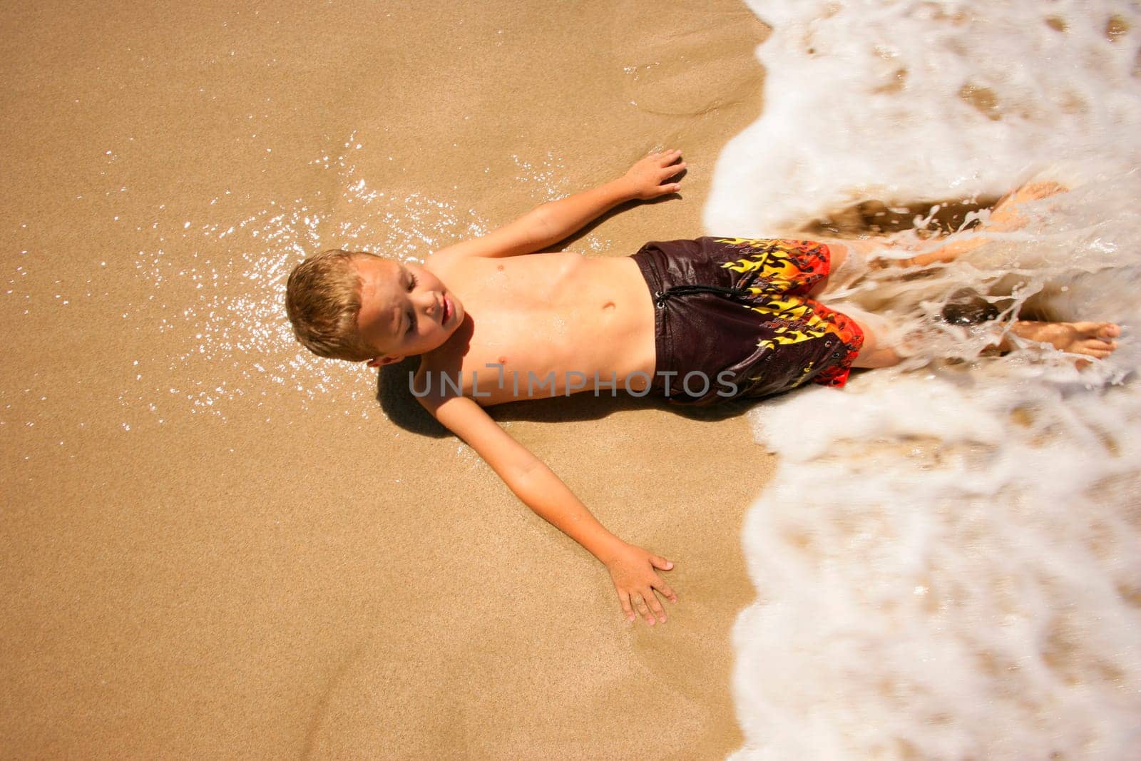 Boy lying on beach in water