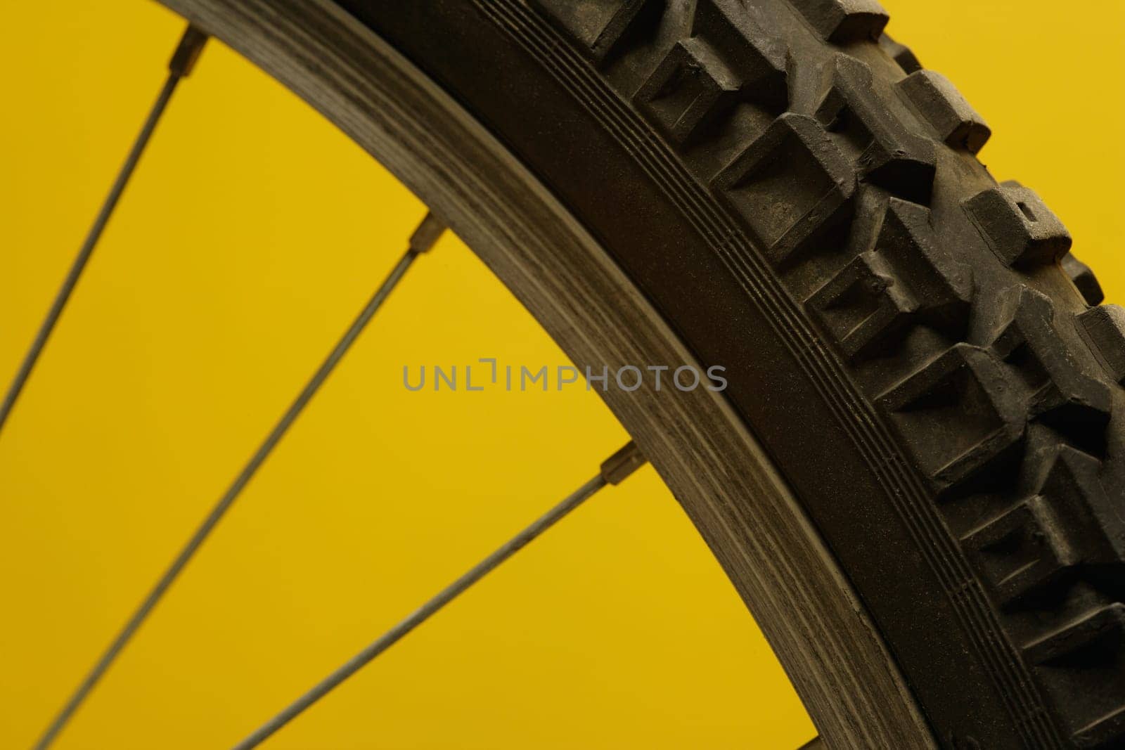 Part of a bicycle wheel against a yellow background
