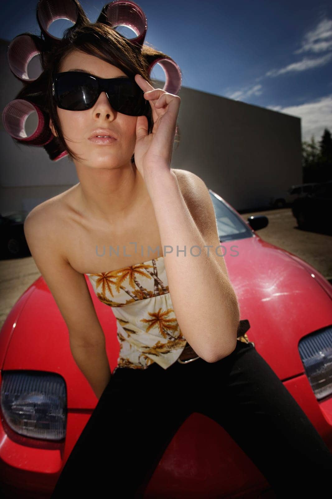 A young woman sitting on the hood of a sports car