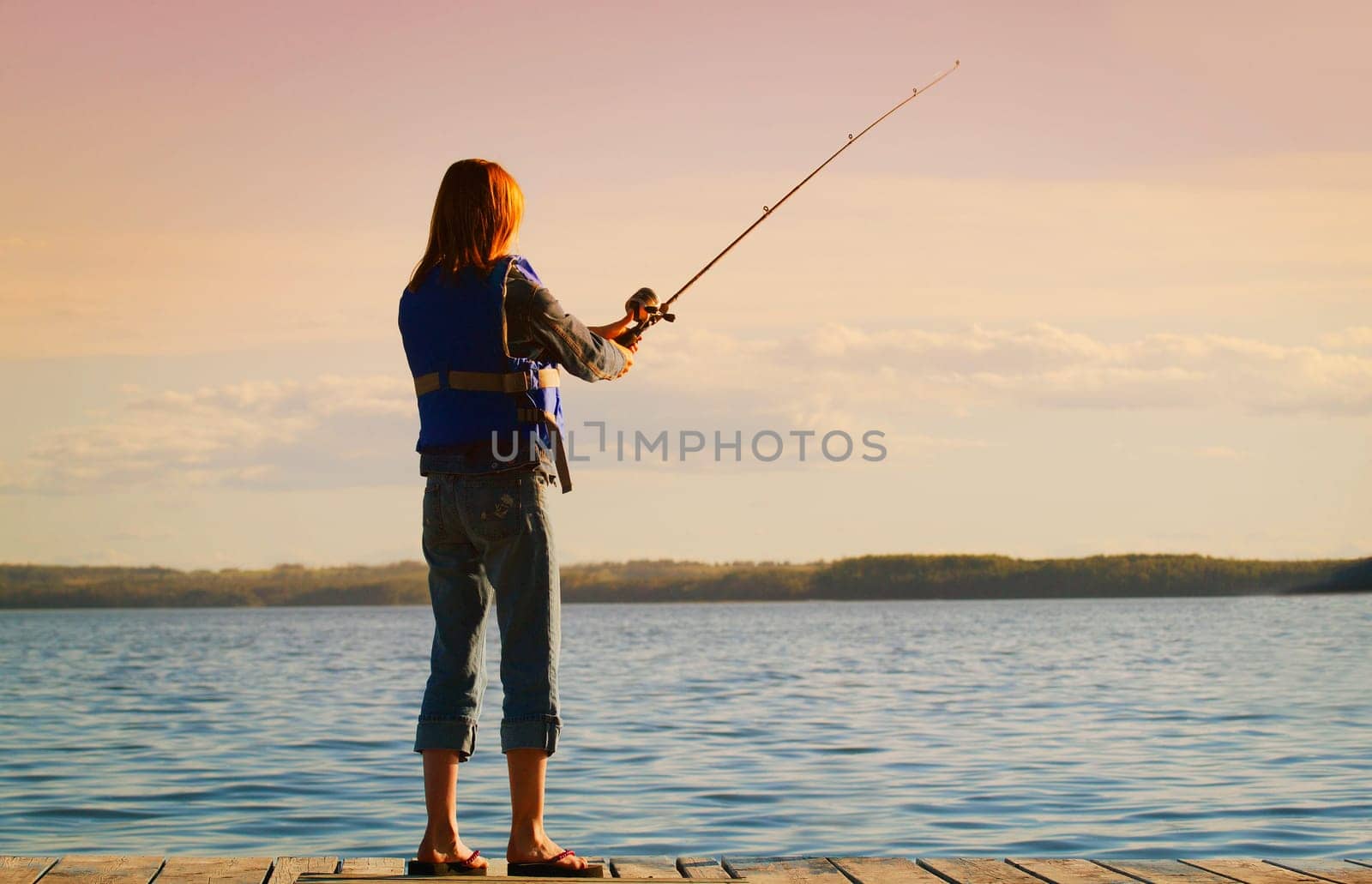A young woman fishing off a dock