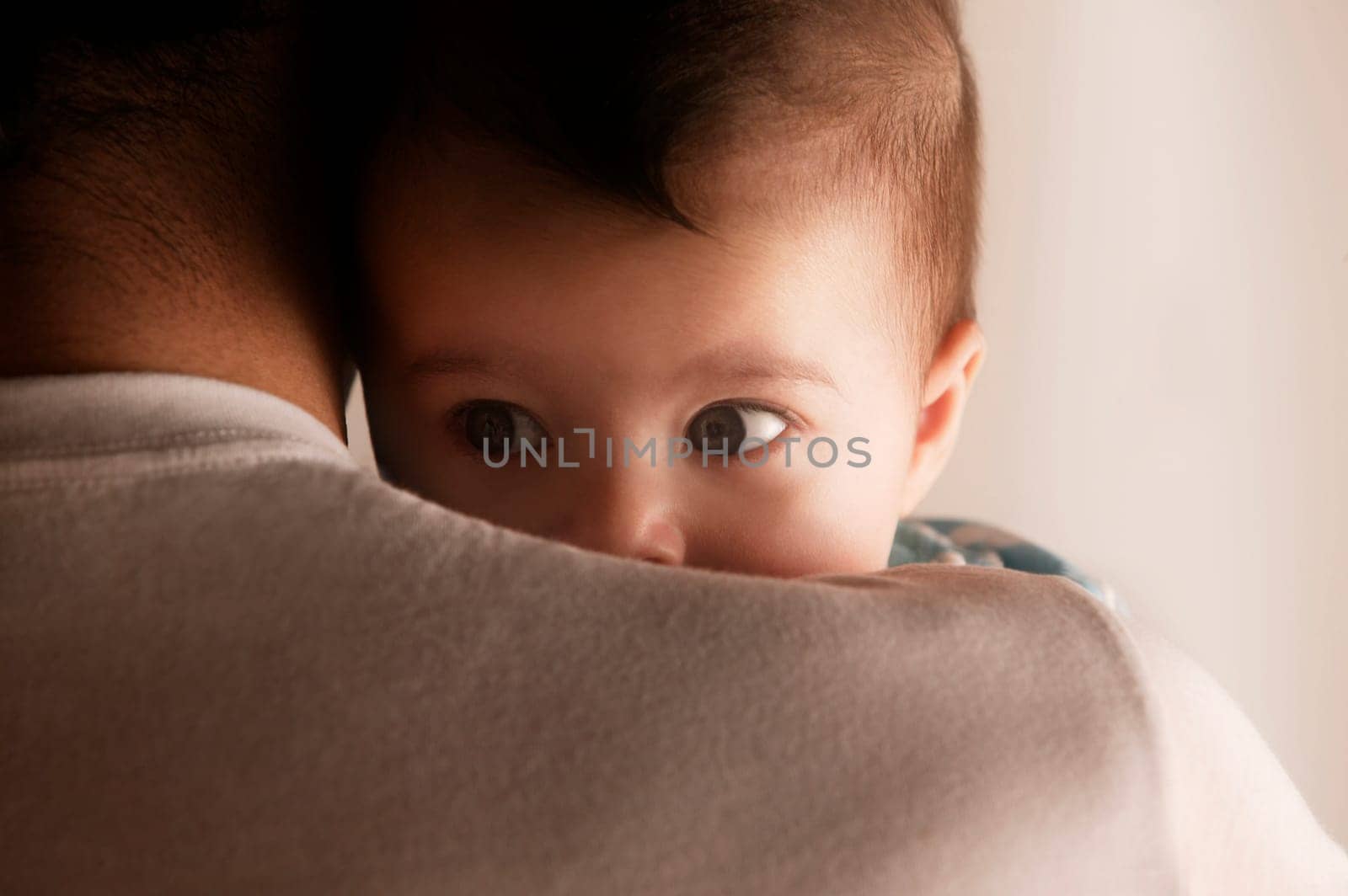 Baby peering over dads shoulder