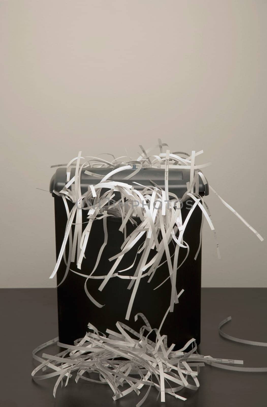 An overflowing garbage can of shredded paper