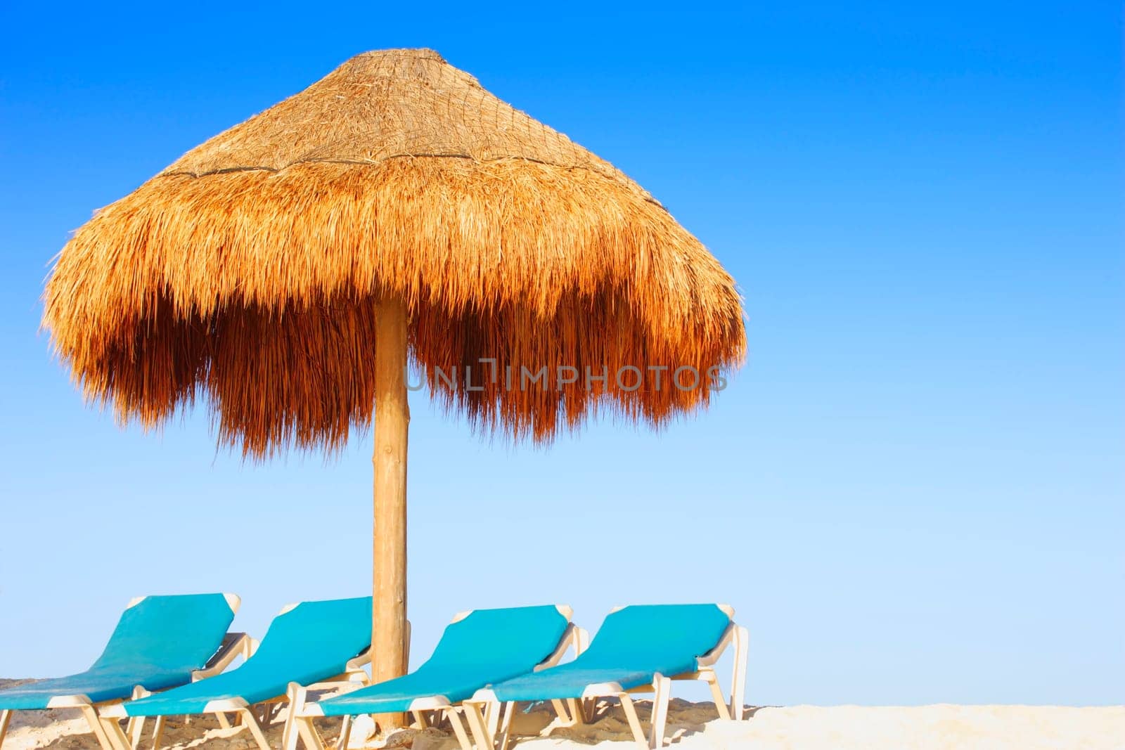 Palm hut and chairs on tropical beach