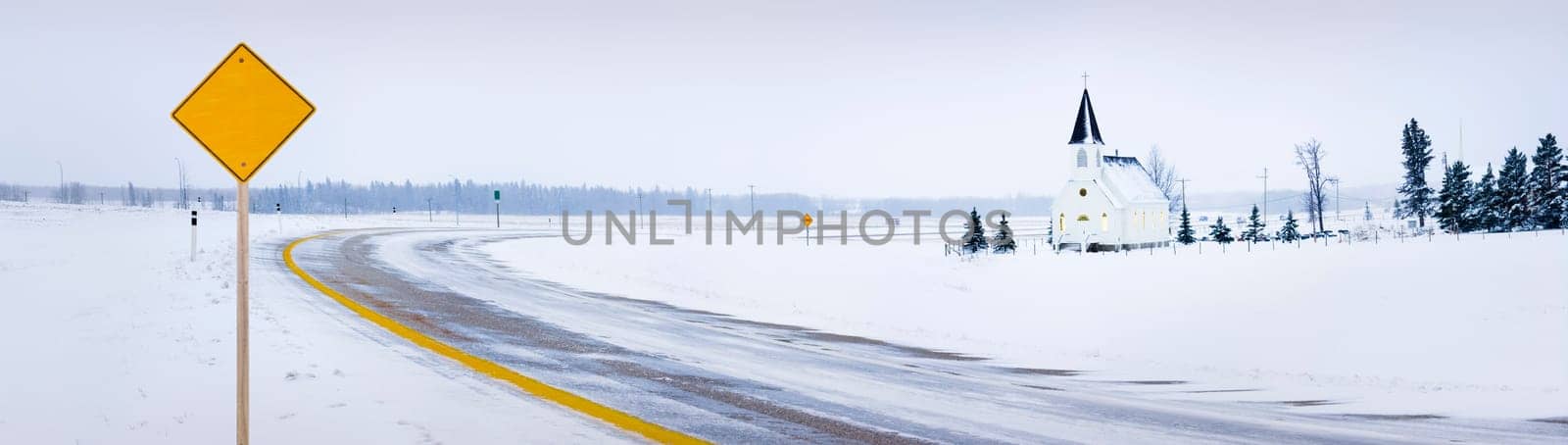 Old fashioned steeple church with road in winter