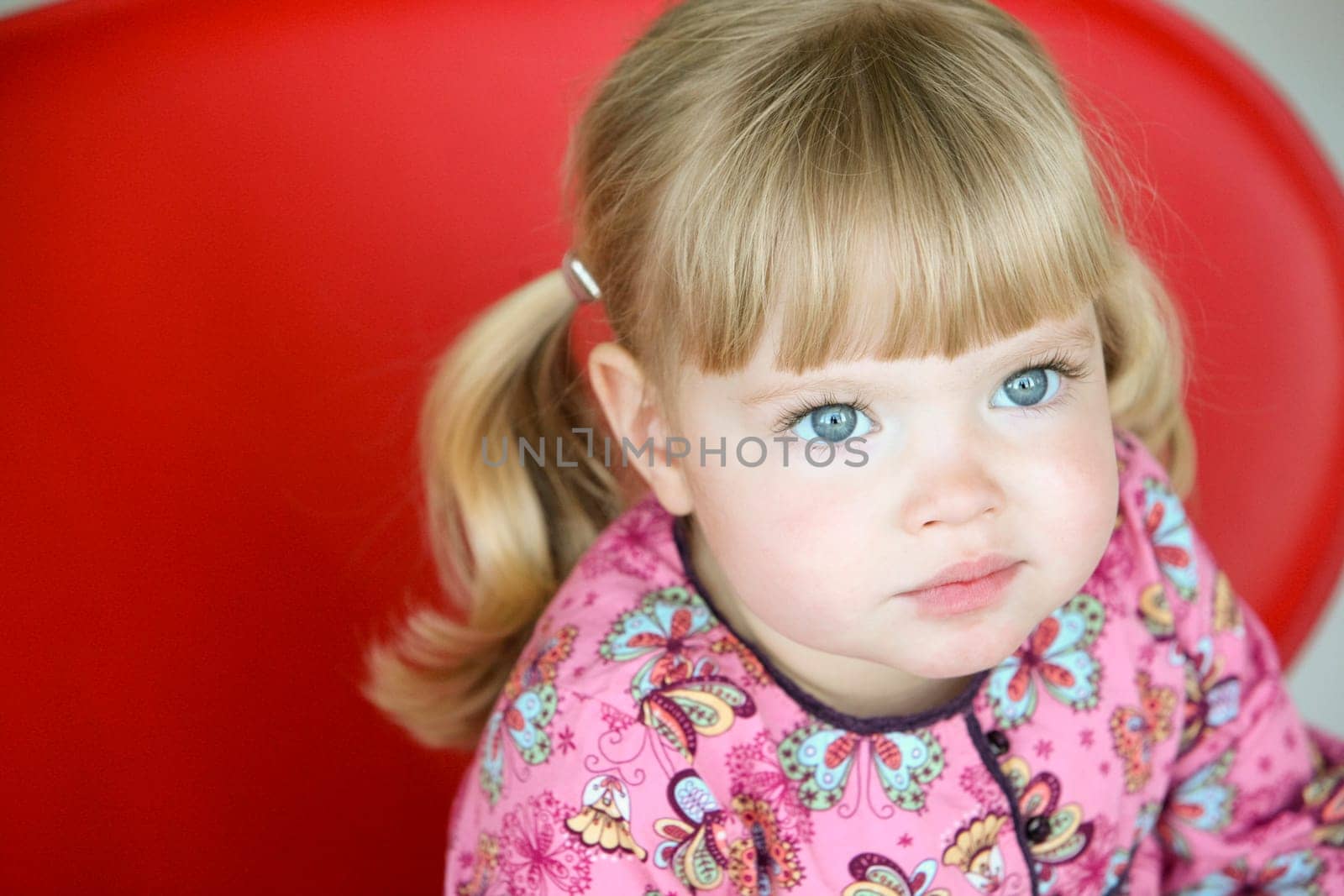 Little girl sitting on a red chair