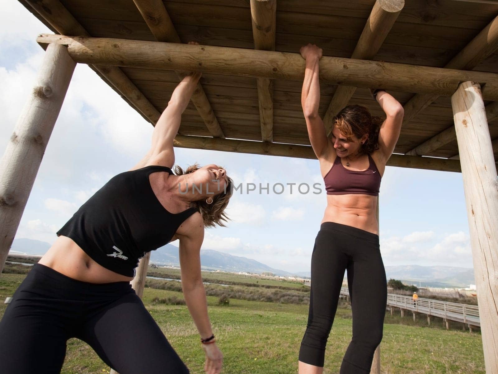 Two women hanging from wooden structure