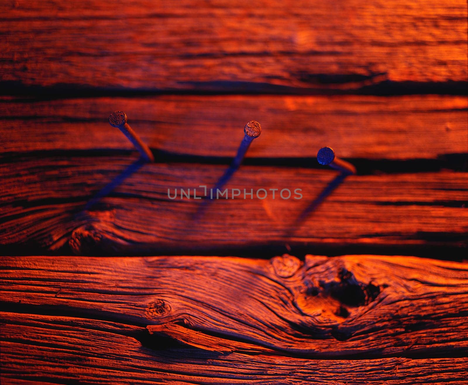 Three nails in wood in red tones