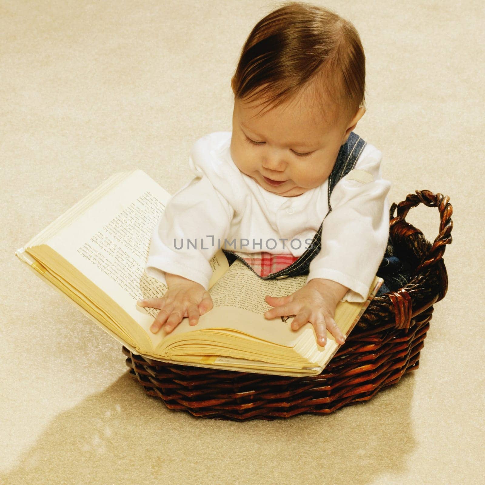 Baby reading a book in a basket