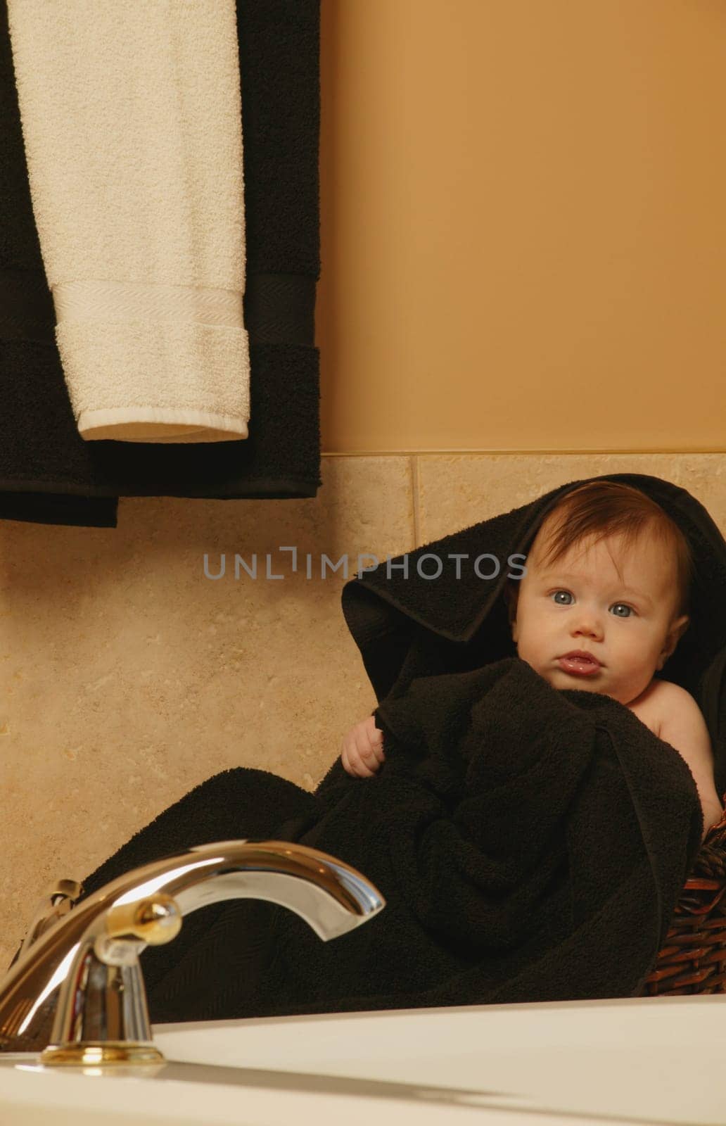 Baby sits wrapped in towel