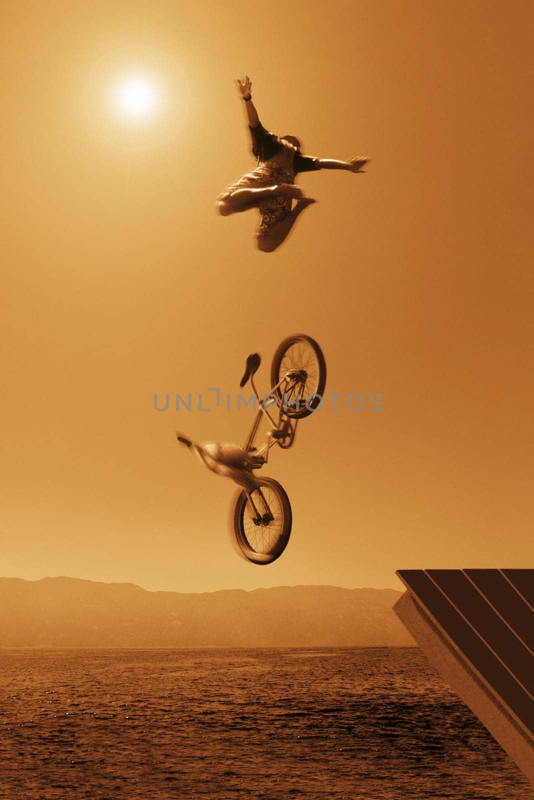Cyclist going off jump into water in brown tones
