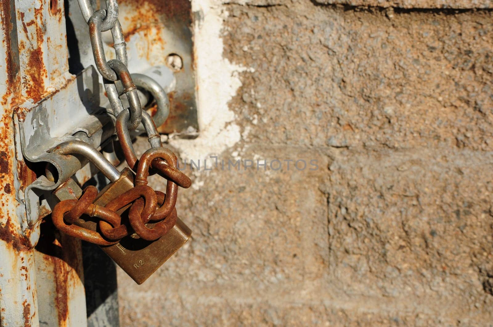 rusty chain and lock against a cement brick wall