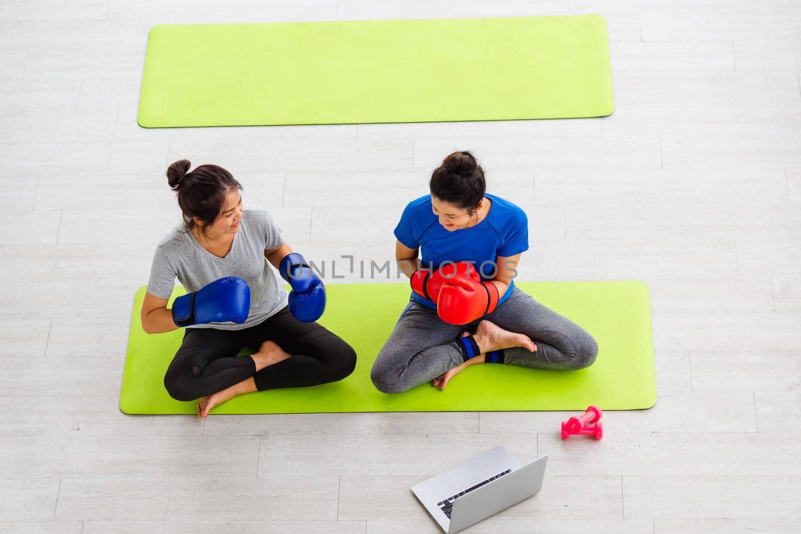 Overhead Asian lifestyle adult and young woman sports fitness boxer wearing gloves on boxing in sportswear look laptop computer for training online indoor yoga studio, sport healthy workout concept