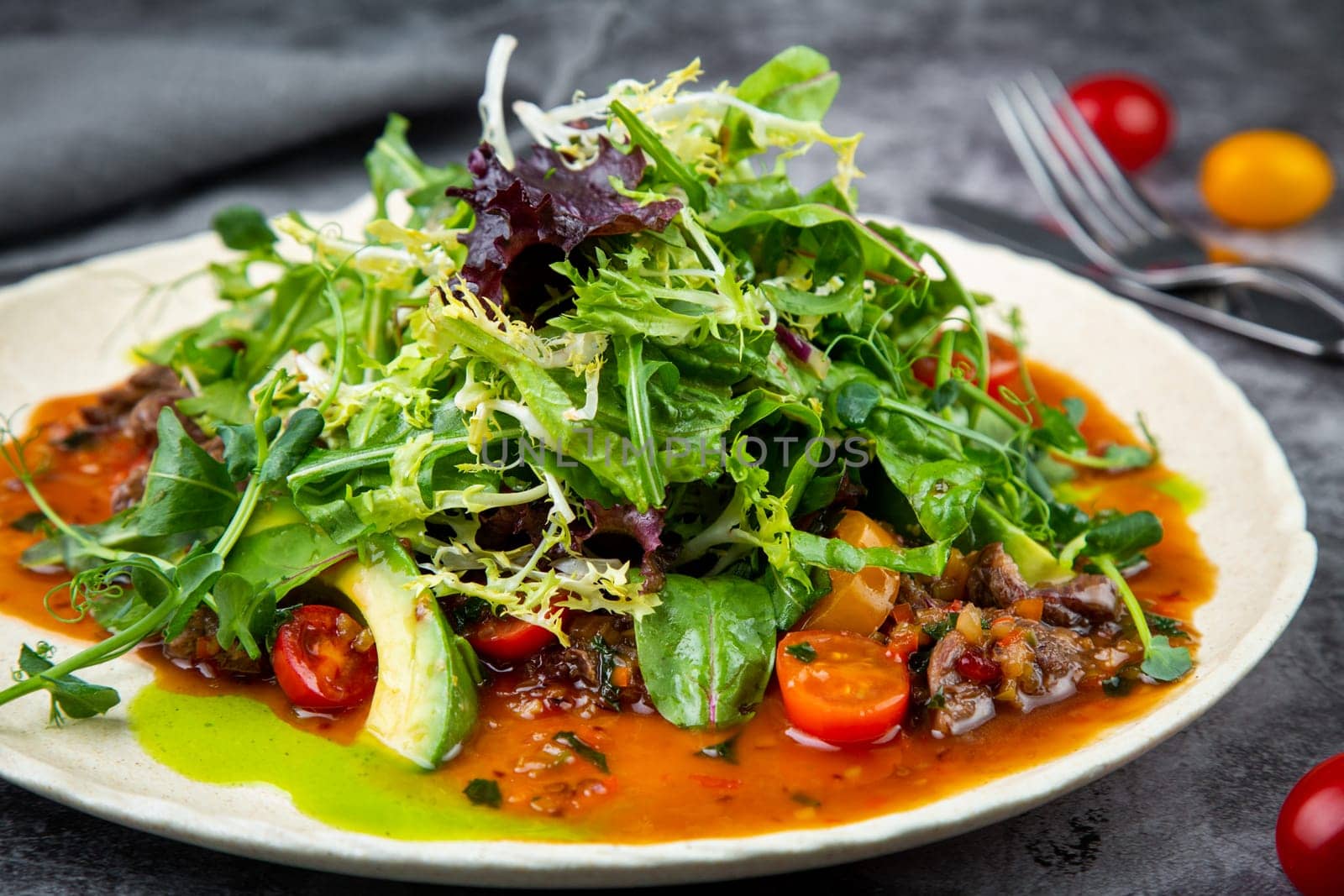 salad of arugula, lettuce leaves, cherry tomatoes and avocado, side view by tewolf