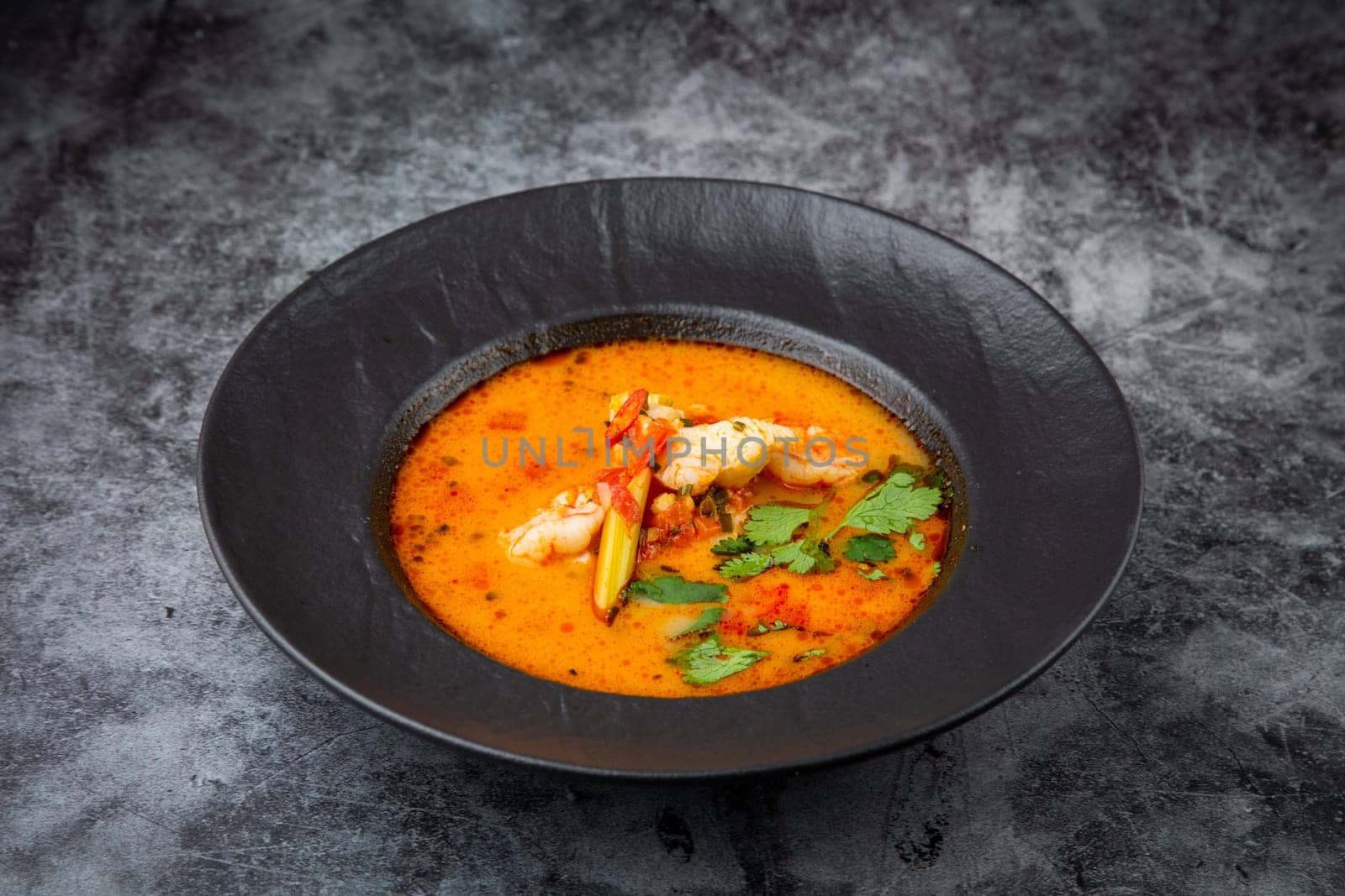 tom yam soup with chicken, lime, cherry tomatoes and parsley side view by tewolf