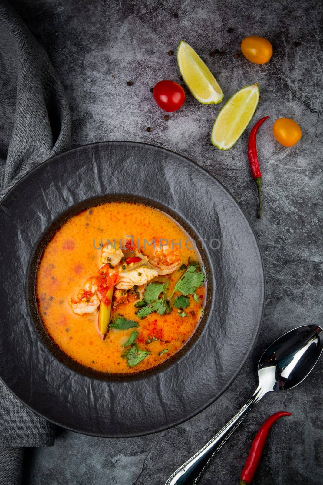 tom yam soup with chicken, lime, cherry tomatoes and parsley top view by tewolf