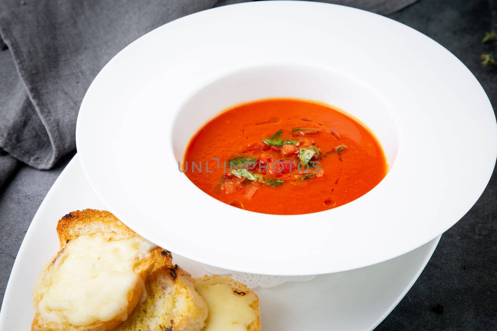 red tomato cream soup with herbs and toasted bread side view by tewolf