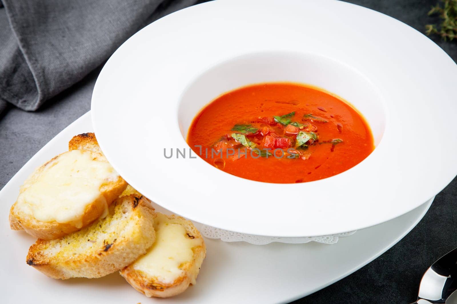 red tomato cream soup with herbs and toasted bread side view by tewolf