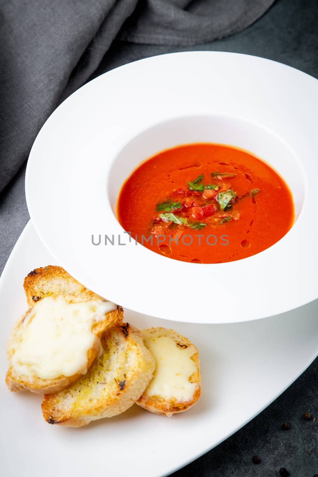 red tomato cream soup with herbs and toasted bread side view by tewolf