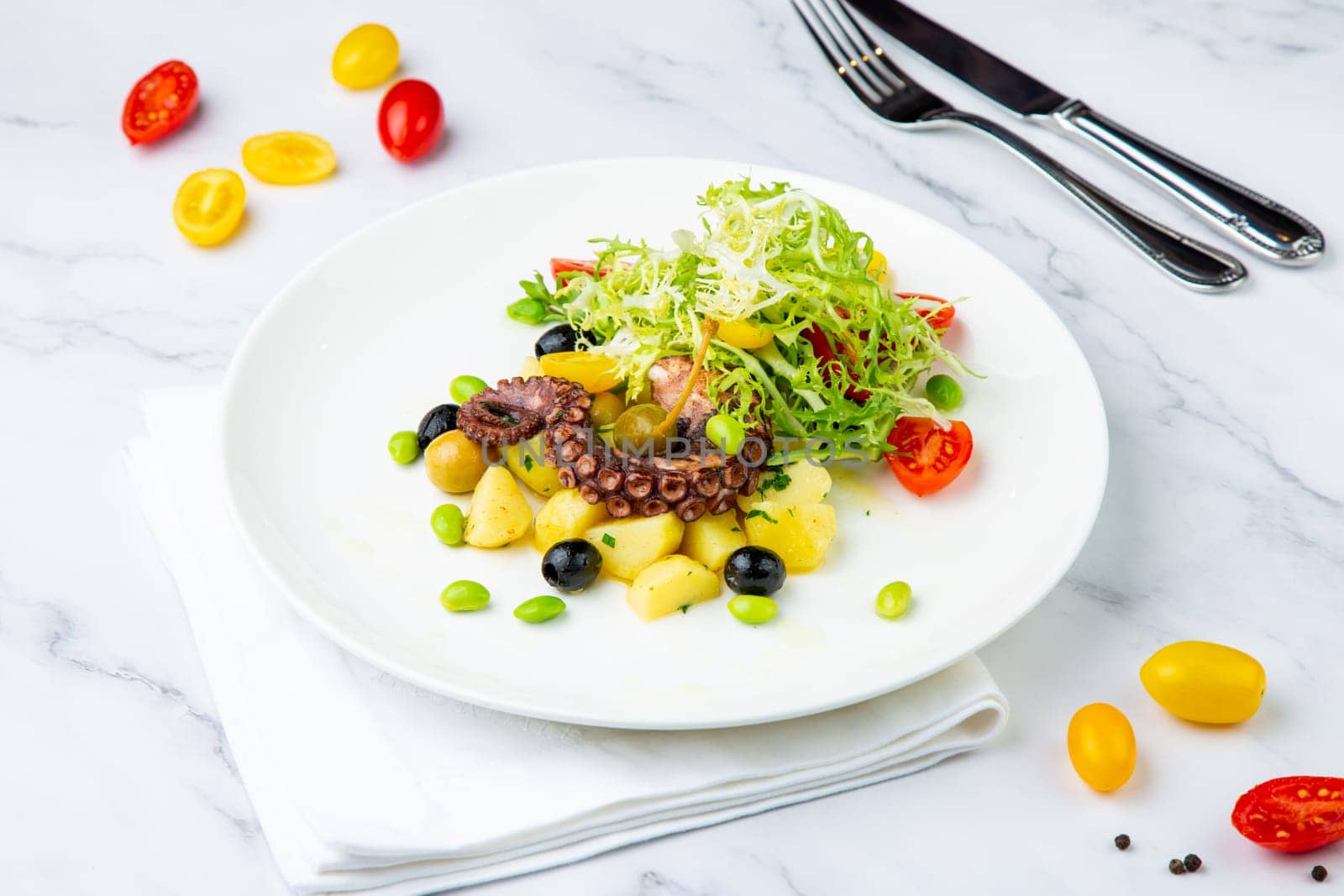 salad with olives, herbs, cherry tomatoes, potatoes and octopus tentacles