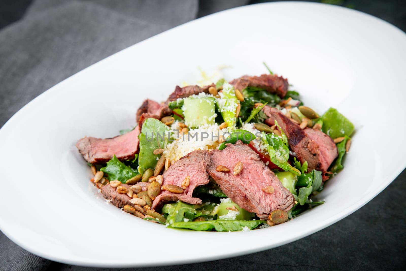 salad with pieces of beef, pistachios, lettuce and cheese side view by tewolf