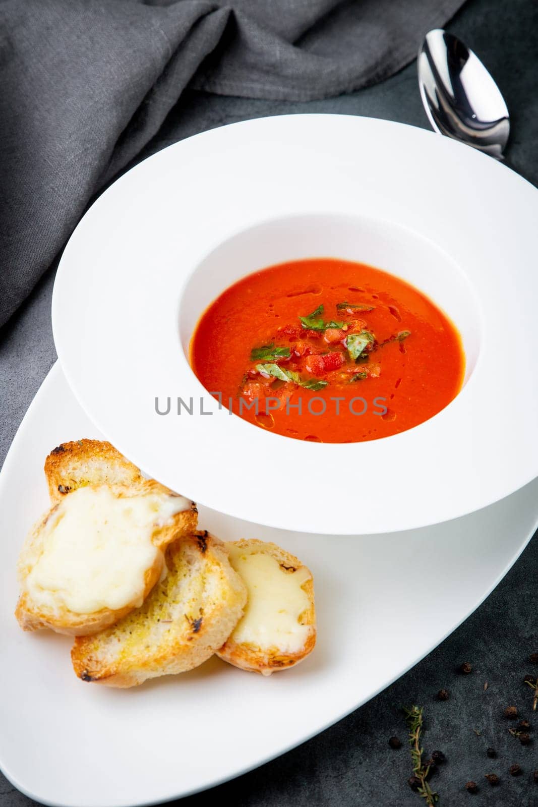 red tomato cream soup with herbs and toasted bread side view by tewolf