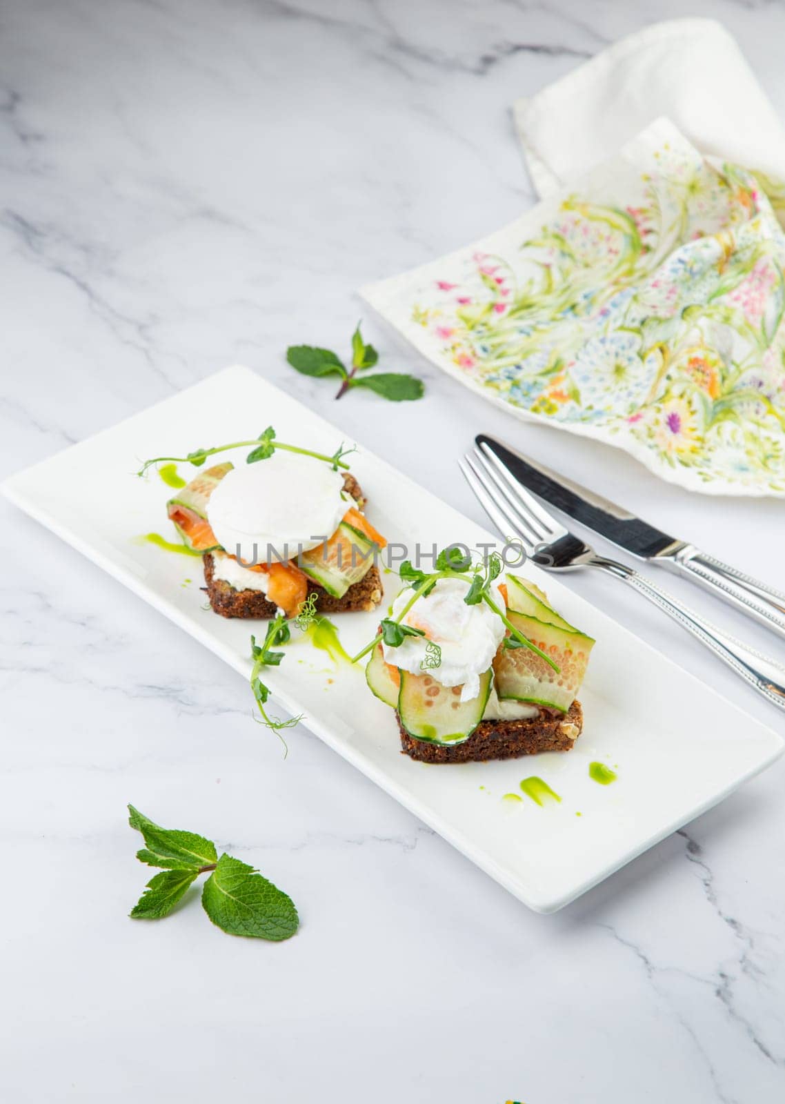 canapes on black bread with cheese, red fish, herbs and cucumber